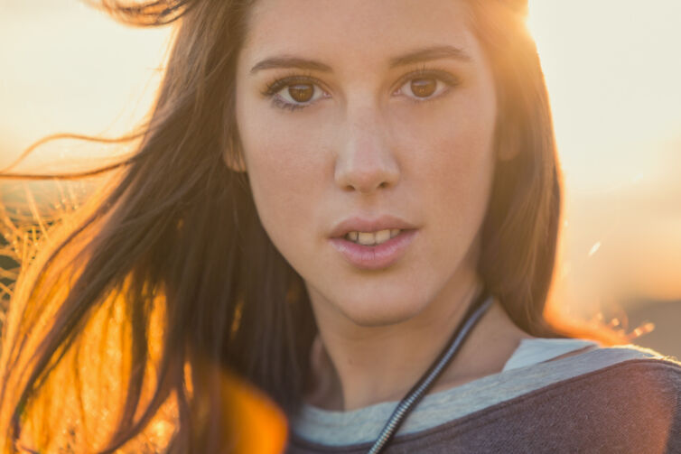 Young smiling brunette hair woman portrait on sunset in nature